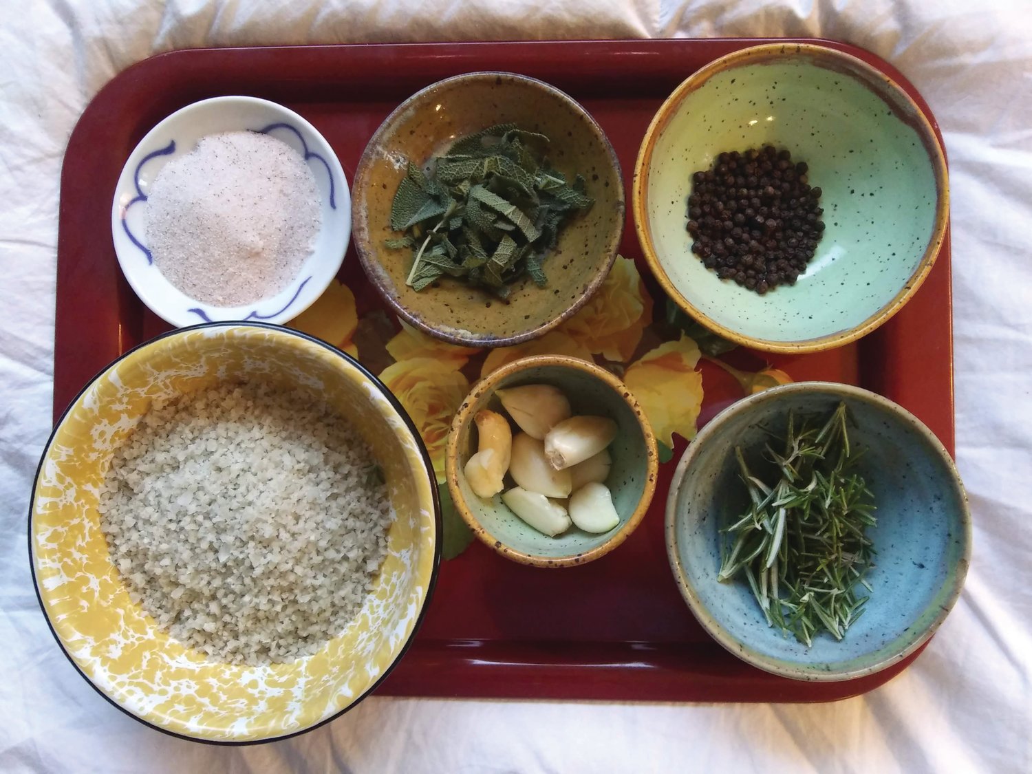 Garlic, peppercorns, sage, rosemary leaves, and other ingredients are ready to be combined for a batch of Sale Alle Erbe delle Port Townsend.